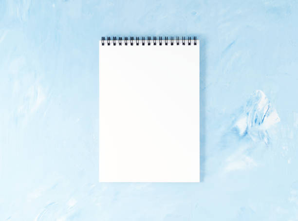 istock Top view of modern bright blue office desktop with notepad. Mock up, empty space 986626960