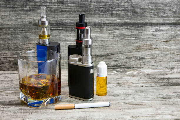 istock Whiskey in a glass with an e-cigarette 986628634
