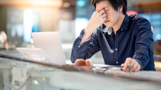 istock Young Asian business man feeling stressed and frustrated while working with laptop computer. Male entrepreneur getting in trouble with his job. freelance lifestyle in urban workspace. 986652948
