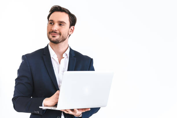 The happy businessman with a laptop standing on the white wall background stock photo