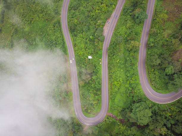 istock Aerial view over mountain road going through forest landscape, Winding road from high mountain pass. Crooked path of road on the mountain, Shot from drone 986660198