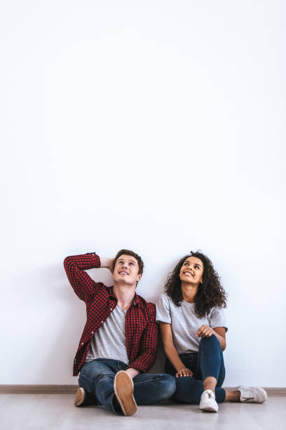 l’heureux couple international assis sur le sol - wall indoors chair floor photos et images de collection