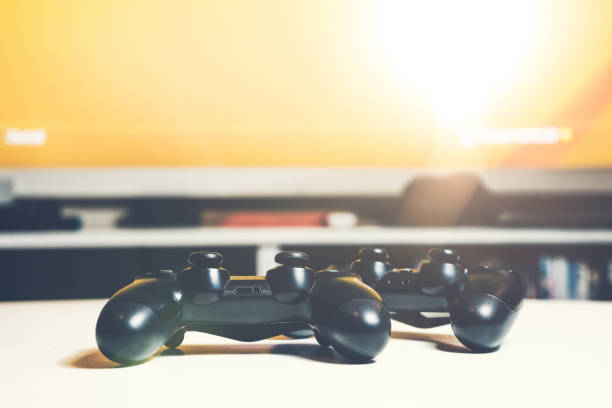 istock Two game controller on a desk with tv in the background 986661758