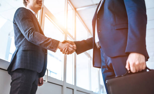 los dos empresarios de saludo en el pasillo de la oficina - warm welcome fotografías e imágenes de stock