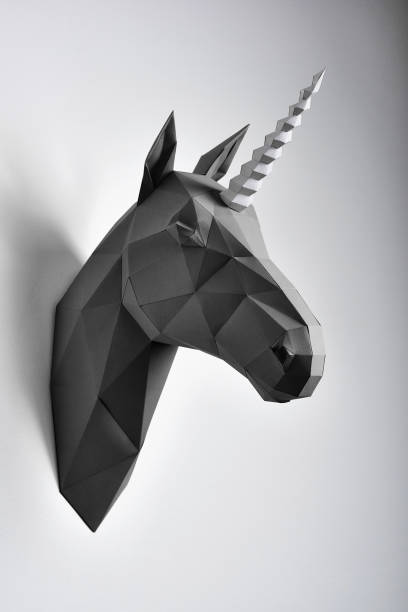 istock Black geometrical unicorn's head paper hanging on grey shadowed wall. 986667782