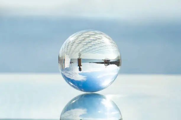 The concept of summer holidays and trips to the resort and the opening of the beach season. A glass ball with reflection of the sea, yachts and sky.