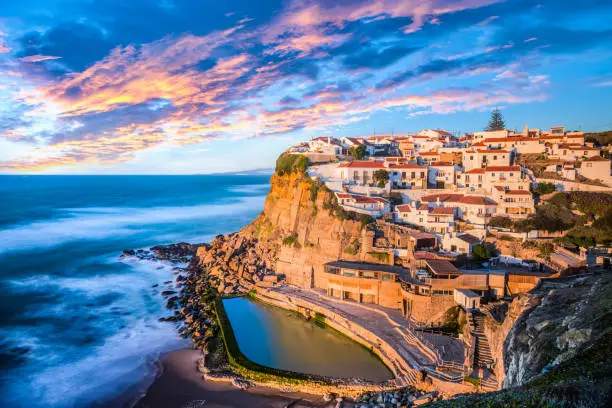 The image shows a beautiful place in Azenhas do mar, in Sintra, near Lisbon on a great sunset with a natural pool.
