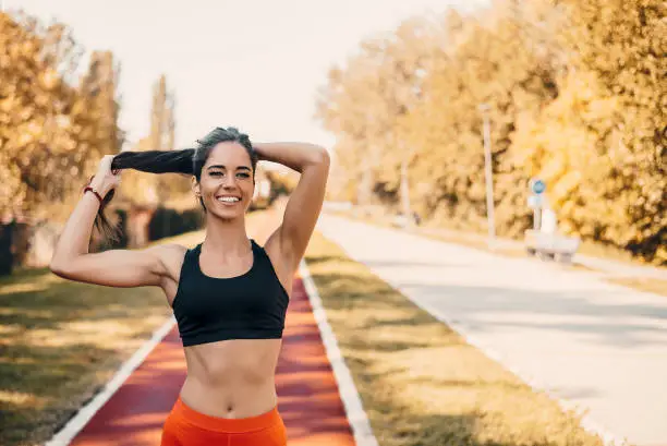 Woman tying hair in ponytail getting ready for run.