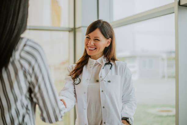 cheerful female patient and doctor shaking hands. - doctor patient greeting talking imagens e fotografias de stock