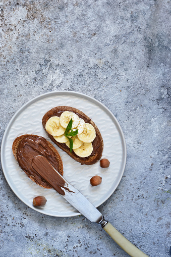 Grilled toast with chocolate paste and banana for breakfast on a concrete background.