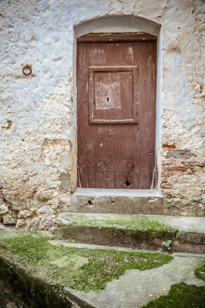 istock Old wooden door, moss-covered steps and stone eroded wall 986686472