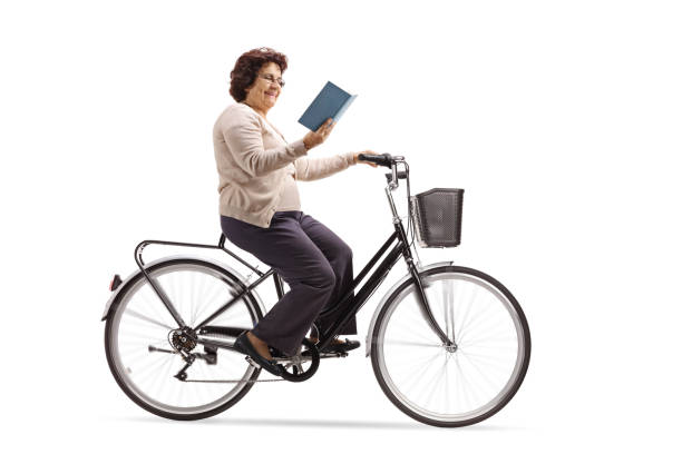 istock Mature woman riding a bicycle and reading a book 986687214