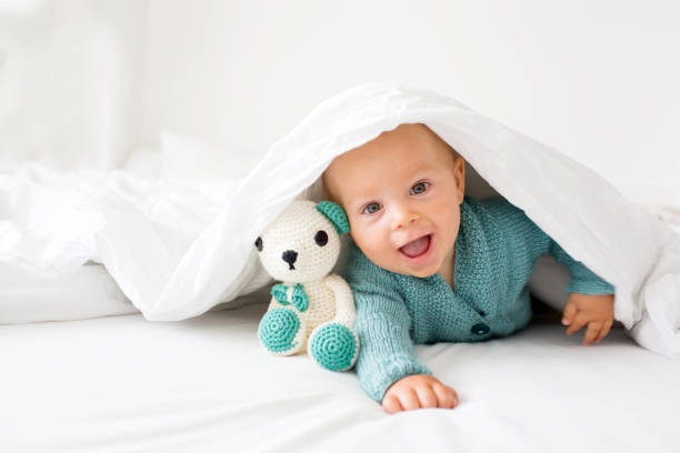 little cute baby boy, child in knitted sweater, holding knitted toy, smiling happily at camera - smiling clothing garment lifestyles imagens e fotografias de stock