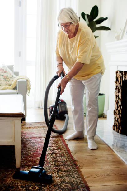 istock Senior woman vacuuming a carpet 986693120