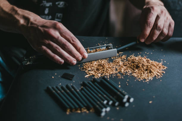 istock Male hands making a cigarettes with machine using fresh tobacco 986697676