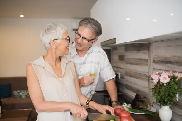 istock Happy mature couple looking at each other while preparing lunch 986704250