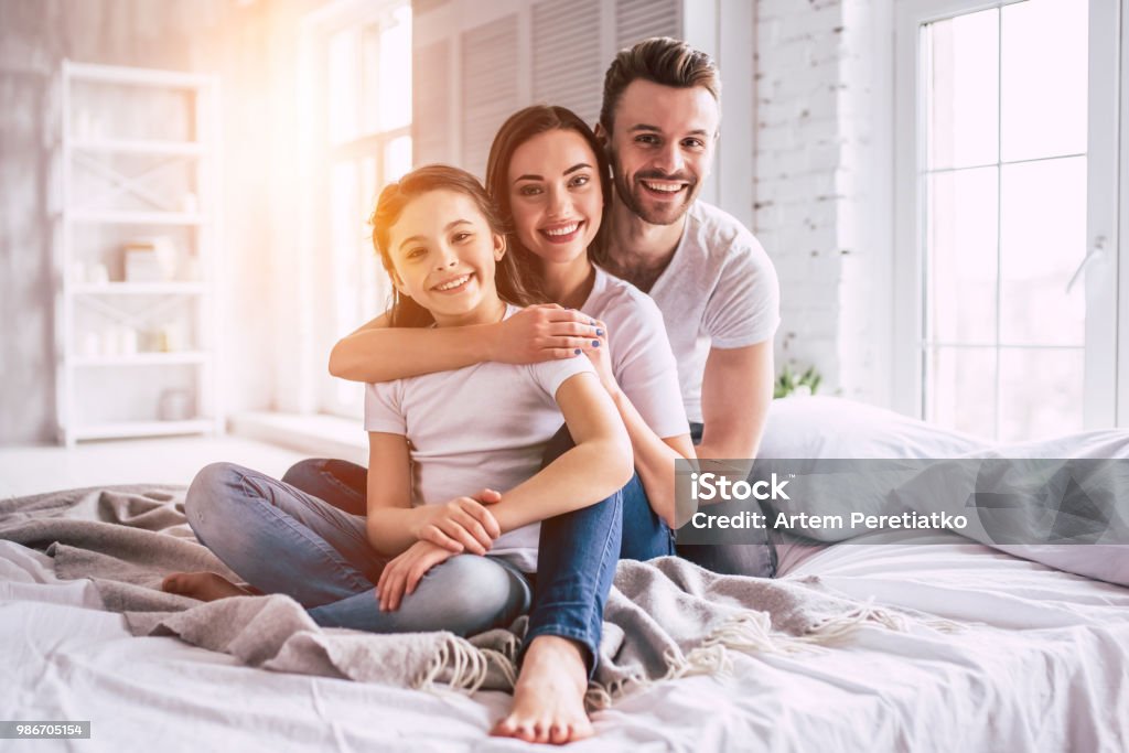 La familia feliz sentado en la cama - Foto de stock de Familia libre de derechos