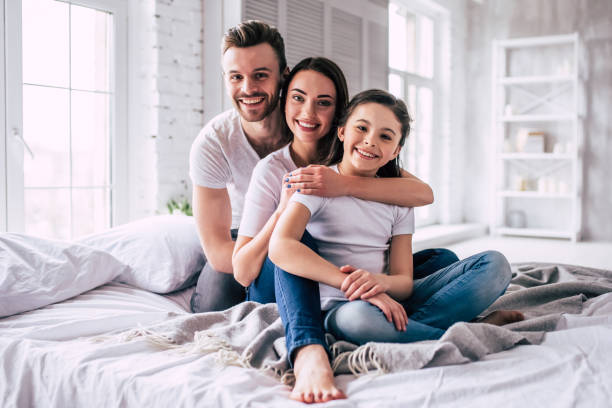 The happy family sitting on the bed stock photo