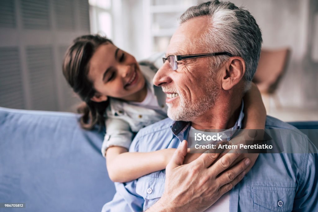The happy girl hugs a grandfather on the sofa Lifestyles Stock Photo