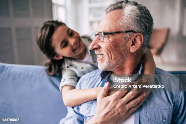 The Happy Girl Hugs A Grandfather On The Sofa Stock Photo - Download Image Now - Lifestyles, Mature Adult, Daughter