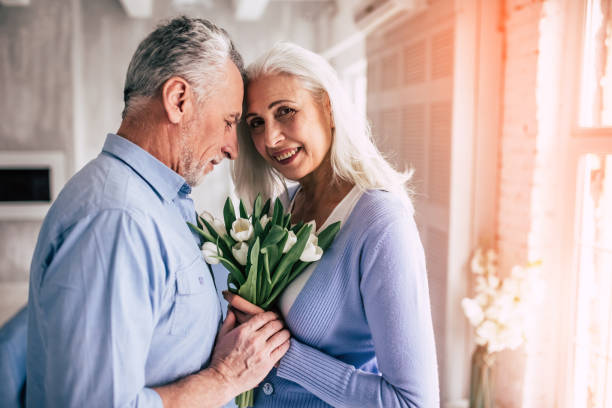 istock The happy elderly couple standing with flowers 986709080