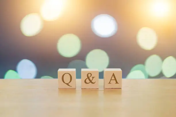 QA questions answers on 3 wooden cubes on a beautiful bokeh blurred background with lights