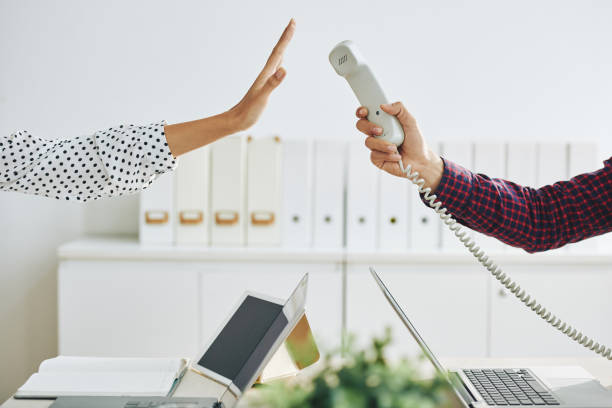 Woman rejecting call in office Crop man outstretching telephone handset to woman showing stop gesture and rejecting to answer call in office indifference stock pictures, royalty-free photos & images