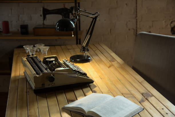 an old typewriter illuminated by a lamp on a wooden lacquered table - electric typewriter imagens e fotografias de stock