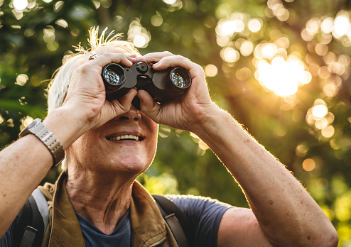 Hombre maduro, observación de aves a través de binoculares photo