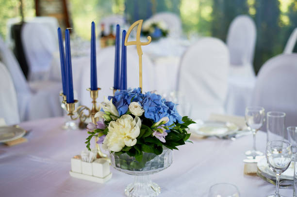 istock Table with a classic design. With a composition in a high vase with hydrangeas and lilies, a Golden candlestick with blue candles.Decor and floristry 986732540