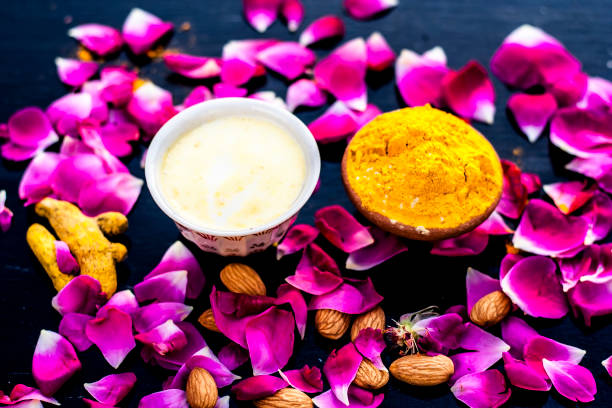 Badam, Haldi & milk ubtan or ayurvedic face maskâs ingredients with ready face pack of Almond with turmeric powder on a black surface removes the dull and black skin. stock photo