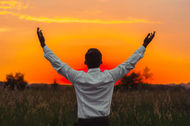 istock a man raises his hands to the sun 986759222