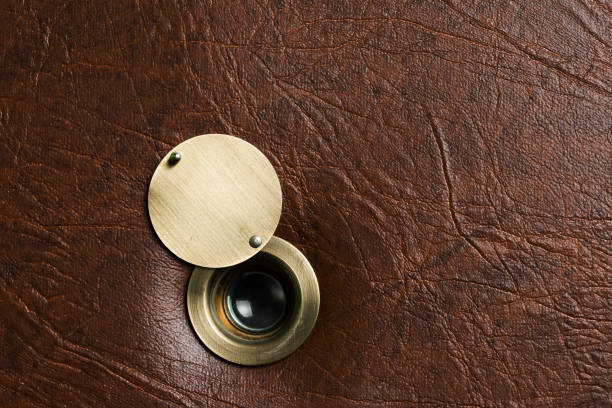 istock Peephole with an open damper on a brown leatherette door 986763992