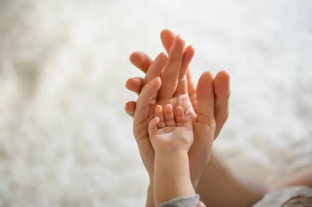 Photo of Close up of parents and baby join hands on the light background