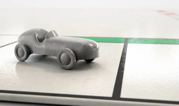 A closeup of a metal die cast car icon on a game board  - 3D render