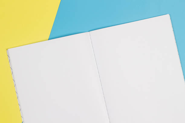 istock Open notebook and colorful notebooks on blue and yellow background 986810656