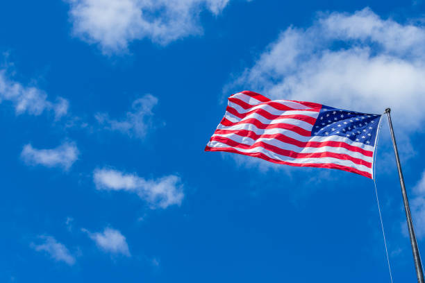 istock American Flag waving with cloudy blue sky on a sunny day 986830408