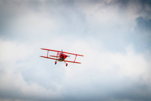 Red propeller airplane flying among the clouds with a storm on the way