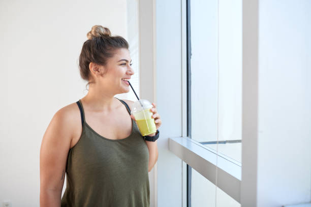 istock Woman with cocktail standing at window 986865800