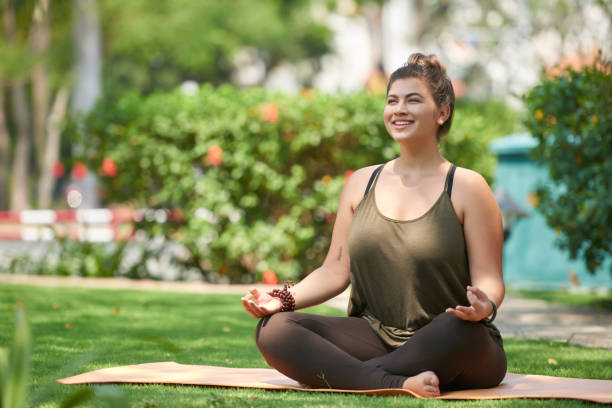 Balance and pacification Beautiful young woman sitting in lotus position on mat in summer park good posture photos stock pictures, royalty-free photos & images
