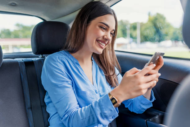istock Nice beautiful young woman smile and use mobile phone touching the screen inside the car while travel 986869648