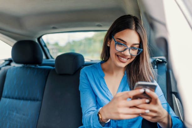 Internet and social media Young girl uses a mobile phone in the car. Technology cell phone isolation. Internet and social media. Woman with smartphone in her car. Girl is using a smartphone back seat photos stock pictures, royalty-free photos & images