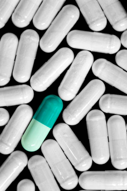 istock Medication singled out multiple white pills with one green pill 986890456