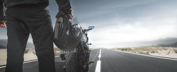 istock Biker with motorcycle on a country road 986894256