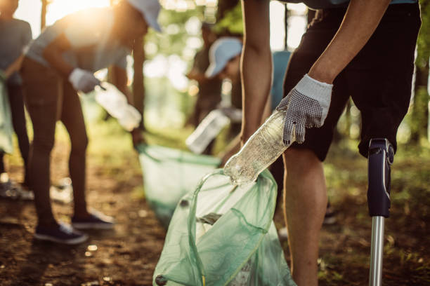 Volunteers cleaning park Group of multi-ethnic people, people with differing abilities , volunteers with garbage bags cleaning park area plastic pollution photos stock pictures, royalty-free photos & images