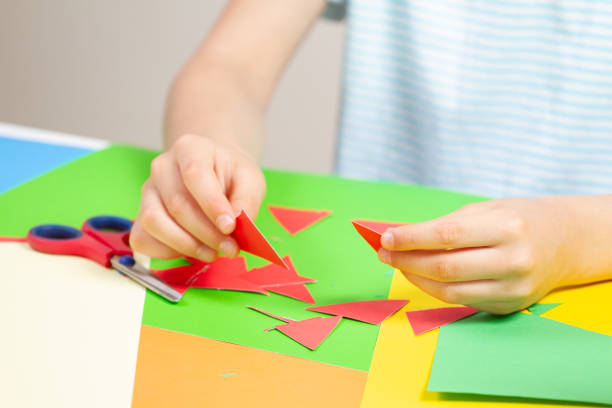 istock Kid hands cutting red color paper 986901908