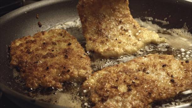 istock Pork Cutlets or Schnitzel Breaded and Frying in a Skillet 986909488