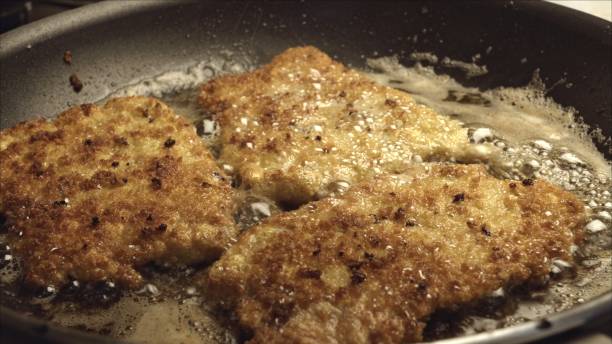 istock Pork Cutlets or Schnitzel Breaded and Frying in a Skillet 986909498