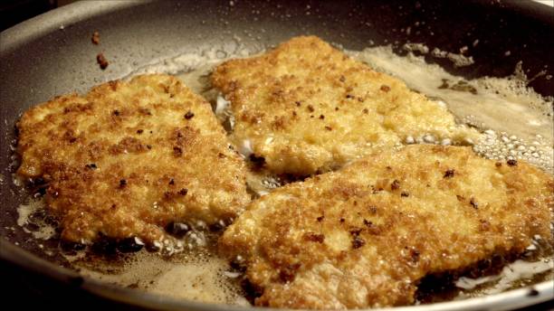 istock Pork Cutlets or Schnitzel Breaded and Frying in a Skillet 986909532