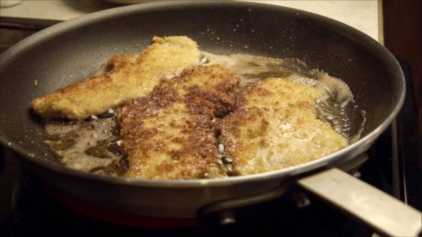 istock Pork Cutlets or Schnitzel Breaded and Frying in a Skillet 986909664